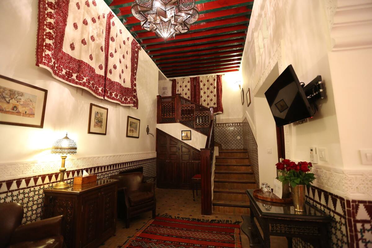 Un interior tradicional con una escalera, muebles de madera y tejidos estampados.