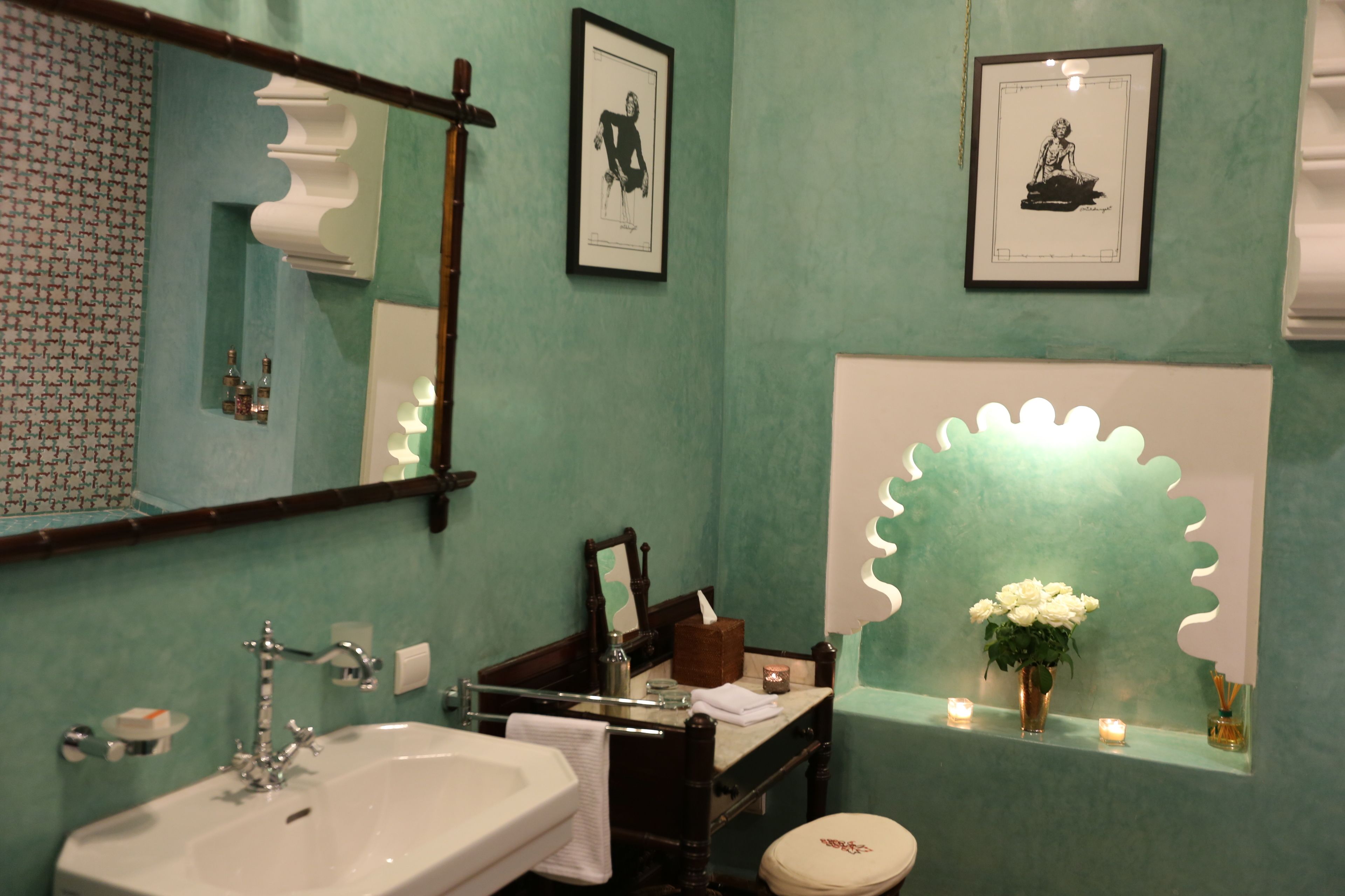 A bathroom with a sink, mirror, framed artwork, and a decorative mirror frame.