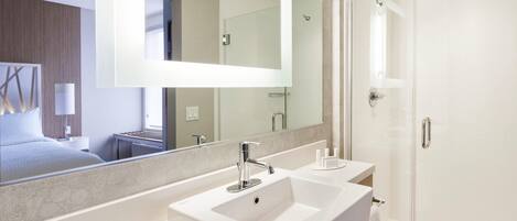 Un baño moderno con un espejo grande, un lavamanos y una ducha.