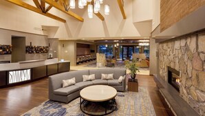 A modern lobby with a stone fireplace, a curved sofa, and a bar area with wine bottles. - Springhill Suites by Marriott Paso Robles Atascadero (Atascadero)