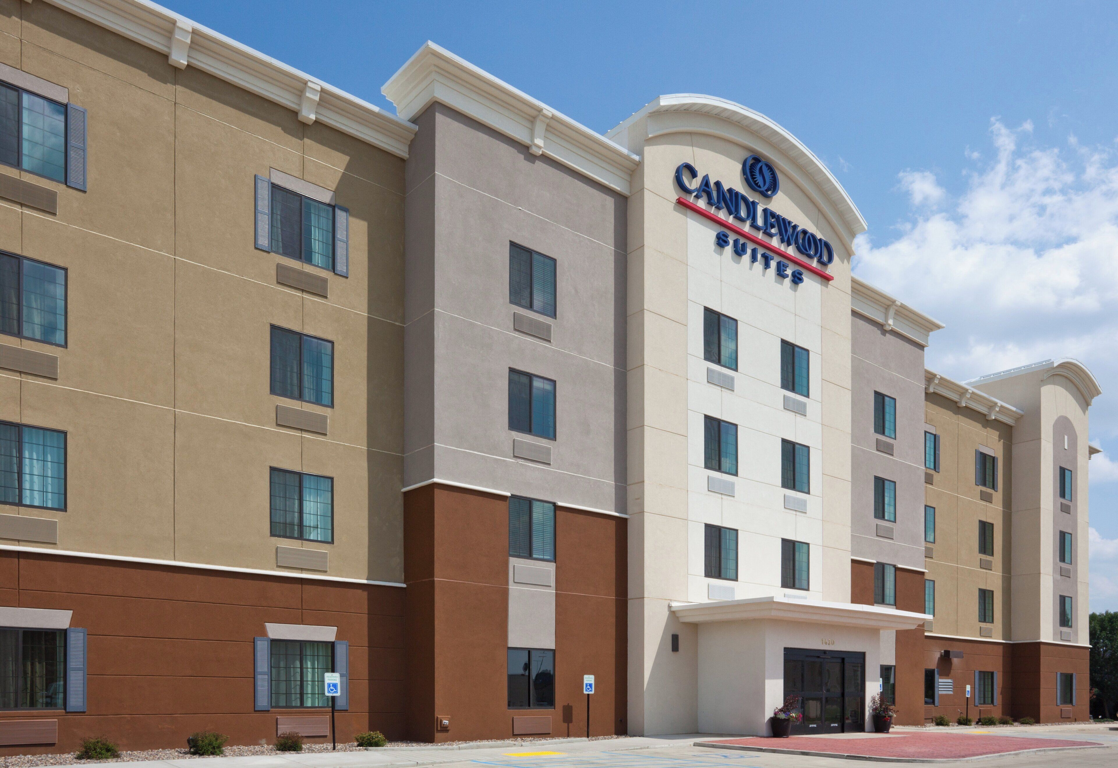 Et hotel med en moderne facade, flere vinduer og tydelig skiltning med 'Candlewood Suites'.