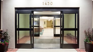A hotel entrance with a number "1430" above the doors, a tiled floor, and two potted plants on either side.