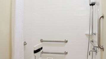 A standard shower stall with a grab bar, a handheld showerhead, and a seat.