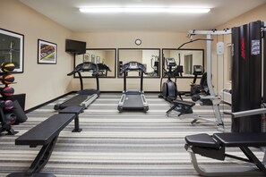 Ein Fitnessstudio mit Laufbändern, Crosstrainern, einer Trainingsbank und Gewährleistungsequipment.