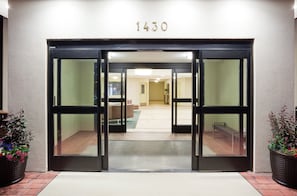 A hotel entrance with a glass door, a number '1430' above, and a carpeted interior leading to a seating area.