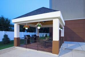 Un patio couvert avec un barbecue et des sièges.