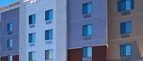 A hotel with a prominent sign reading 'CANDLEWOOD SUITES' and multiple windows on the facade.