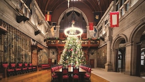 A grand hall with a large Christmas tree, ornate decorations, and a long dining table with red upholstered chairs. - The Inn on Biltmore Estate (Asheville)