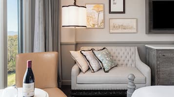 A hotel room with a cushioned seating area, a wine bottle, and framed artwork on the wall.