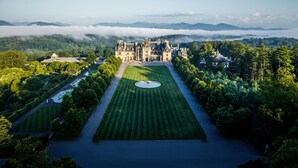 A grand estate with a central lawn, a circular fountain, and a castle-like building. - The Inn on Biltmore Estate (Asheville)