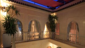 Een meerlaags atrium met gebogen ramen en balkons, met potplanten en een warme, uitnodigende sfeer.