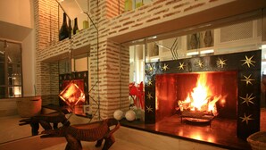 Een modern interieur met een open haard, bakstenen muur en decoratieve elementen.