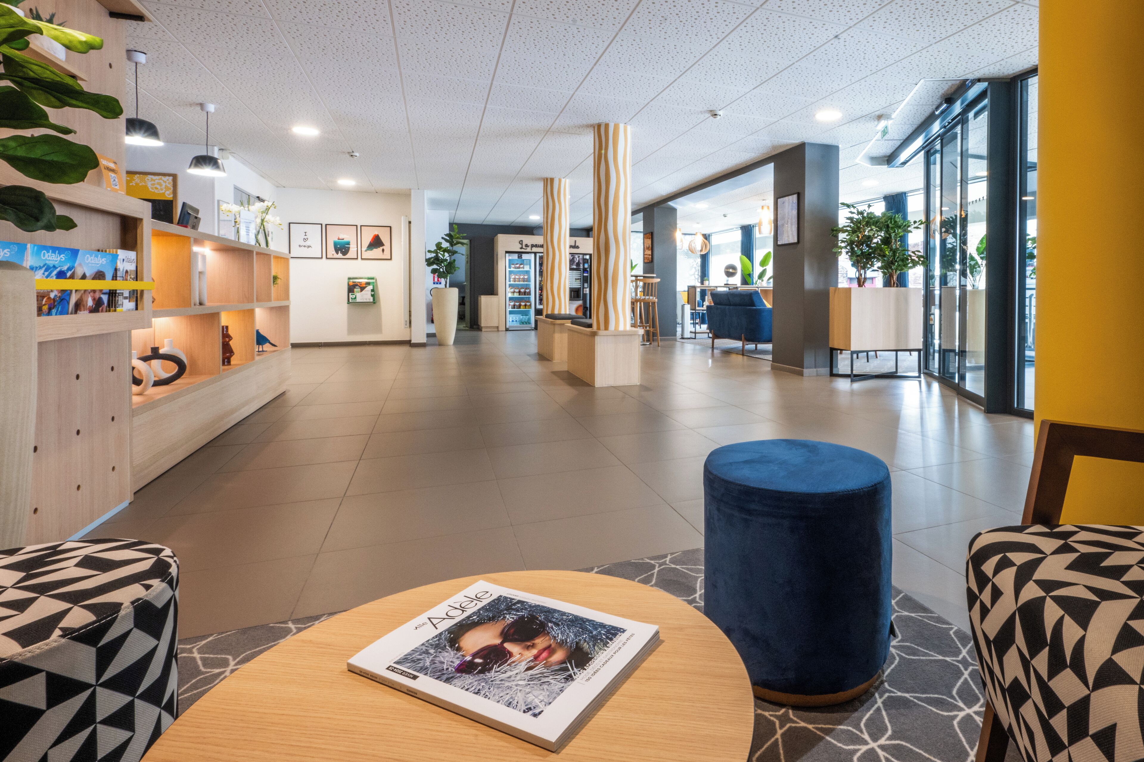 A modern lobby with a reception desk, seating areas, and a magazine on a table.