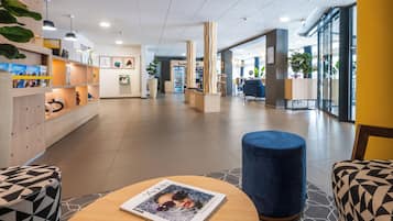 A modern lobby with a reception desk, seating areas, and a magazine on a table.
