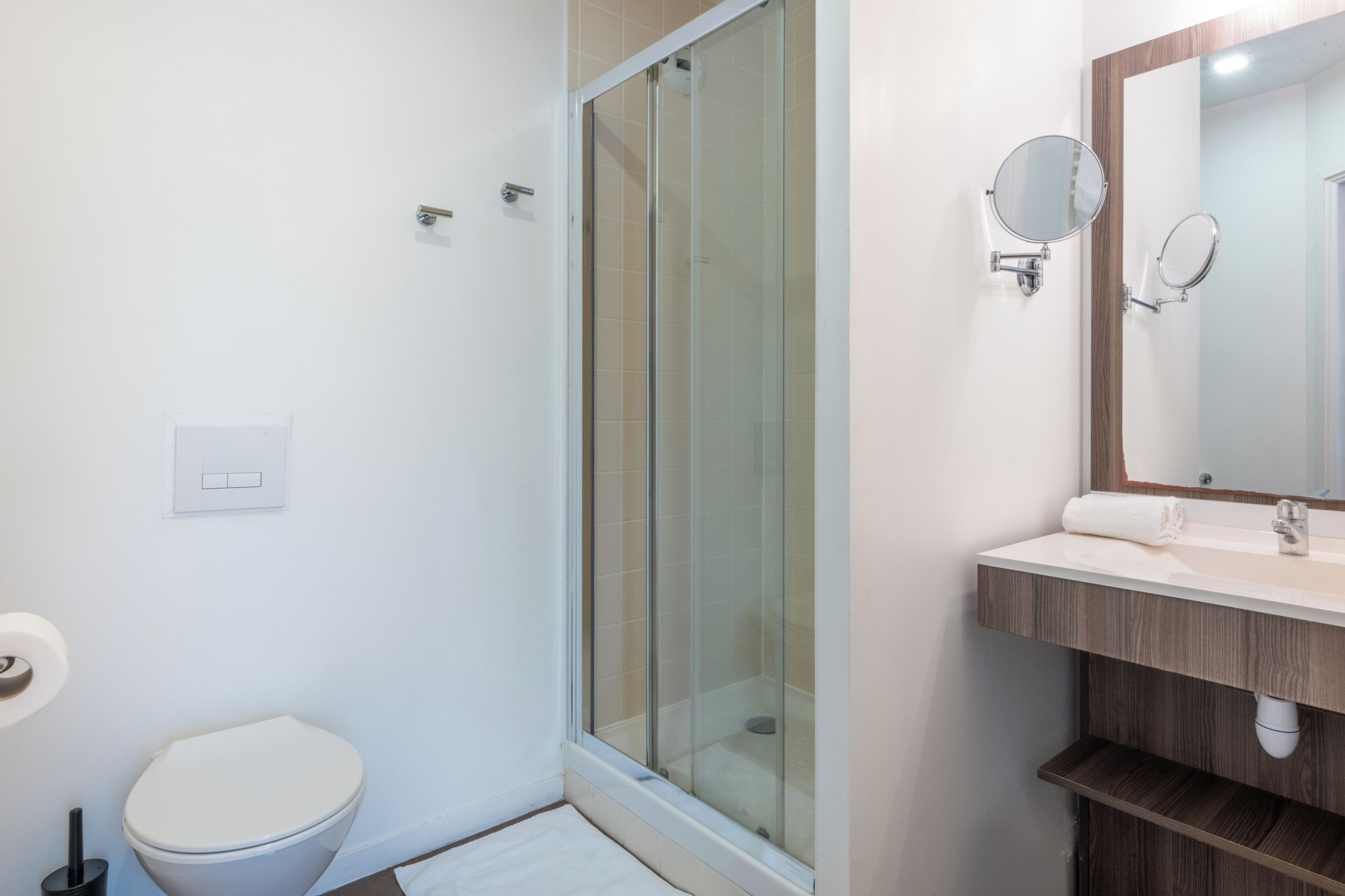 A modern bathroom with a glass shower enclosure, a toilet, and a vanity with a mirror.