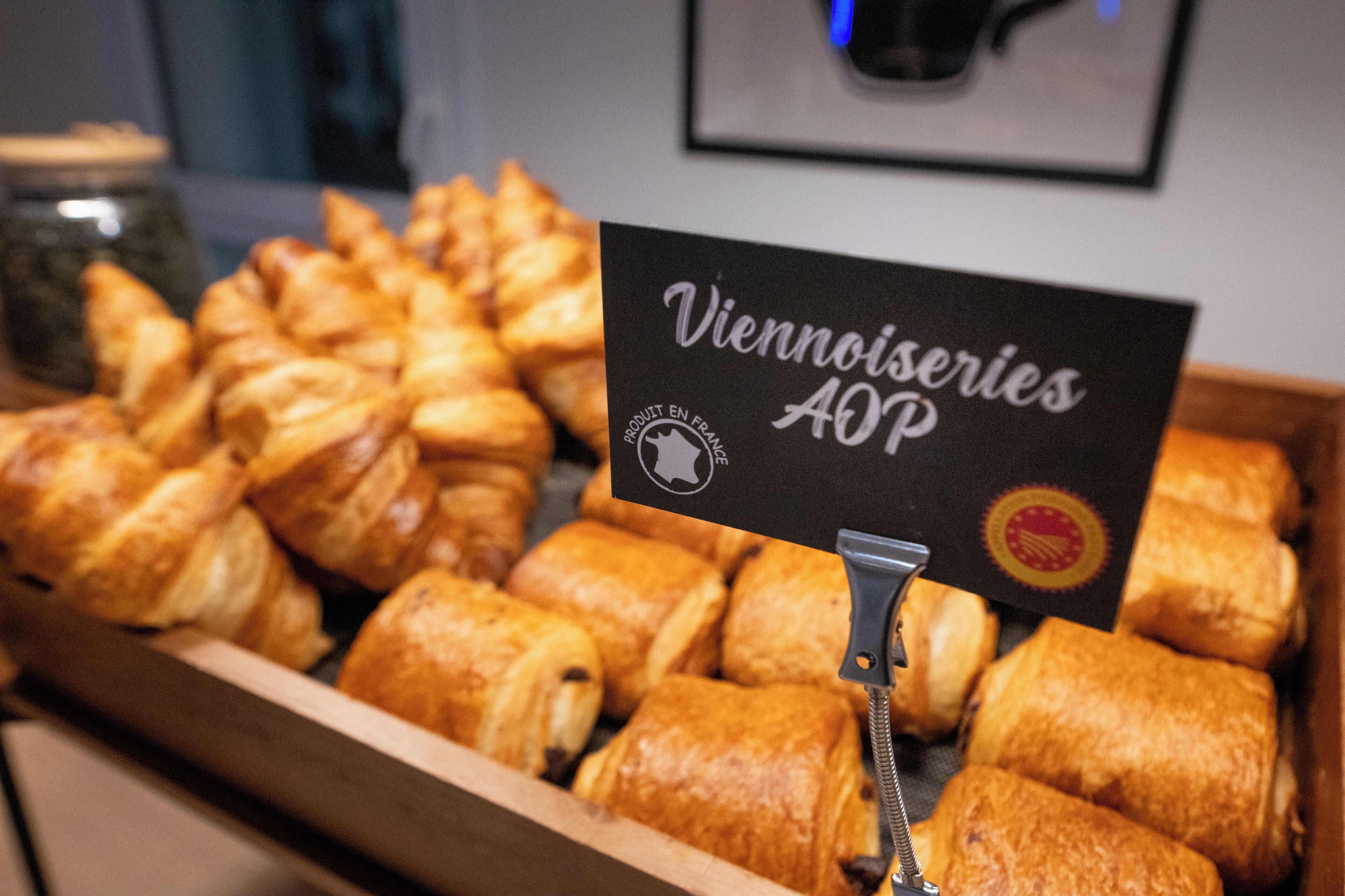A display of various pastries in a wooden box with a sign that reads "Viennoiseries AOP".