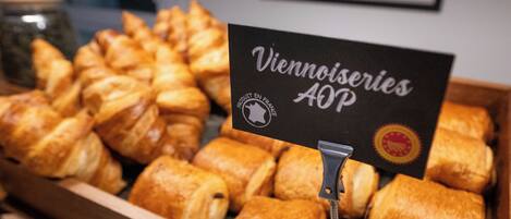 A display of various pastries in a wooden box with a sign that reads "Viennoiseries AOP".