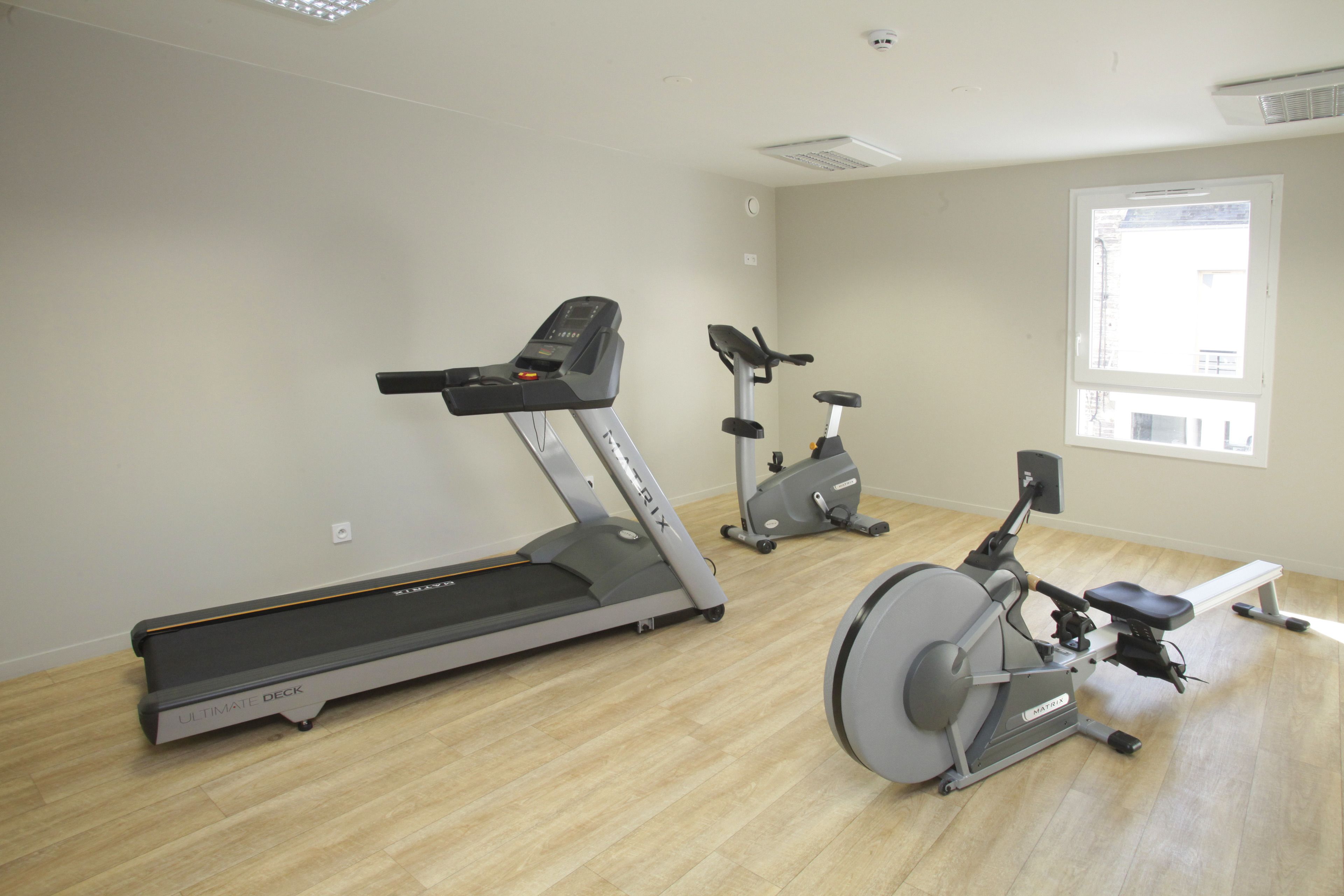 Une salle de sport équipée d’un tapis de course, d’un vélo elliptique et d’un vélo d’appartement.