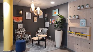 A modern reception area with a geometric-patterned sofa, a round table, and a large potted plant.