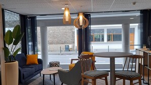 A modern interior with a sofa, chairs, a table, and hanging pendant lights.