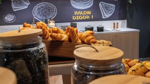A display of pastries and cookies with a chalkboard in the background advertising "BON APPETIT!" and "KALON DIGOR!"