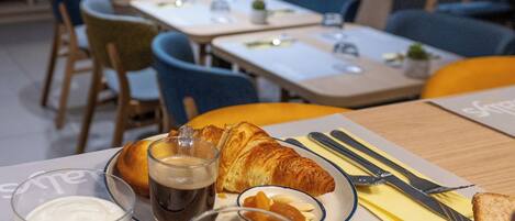 A breakfast setting with croissants, a glass of milk, and a glass of red wine on a table.