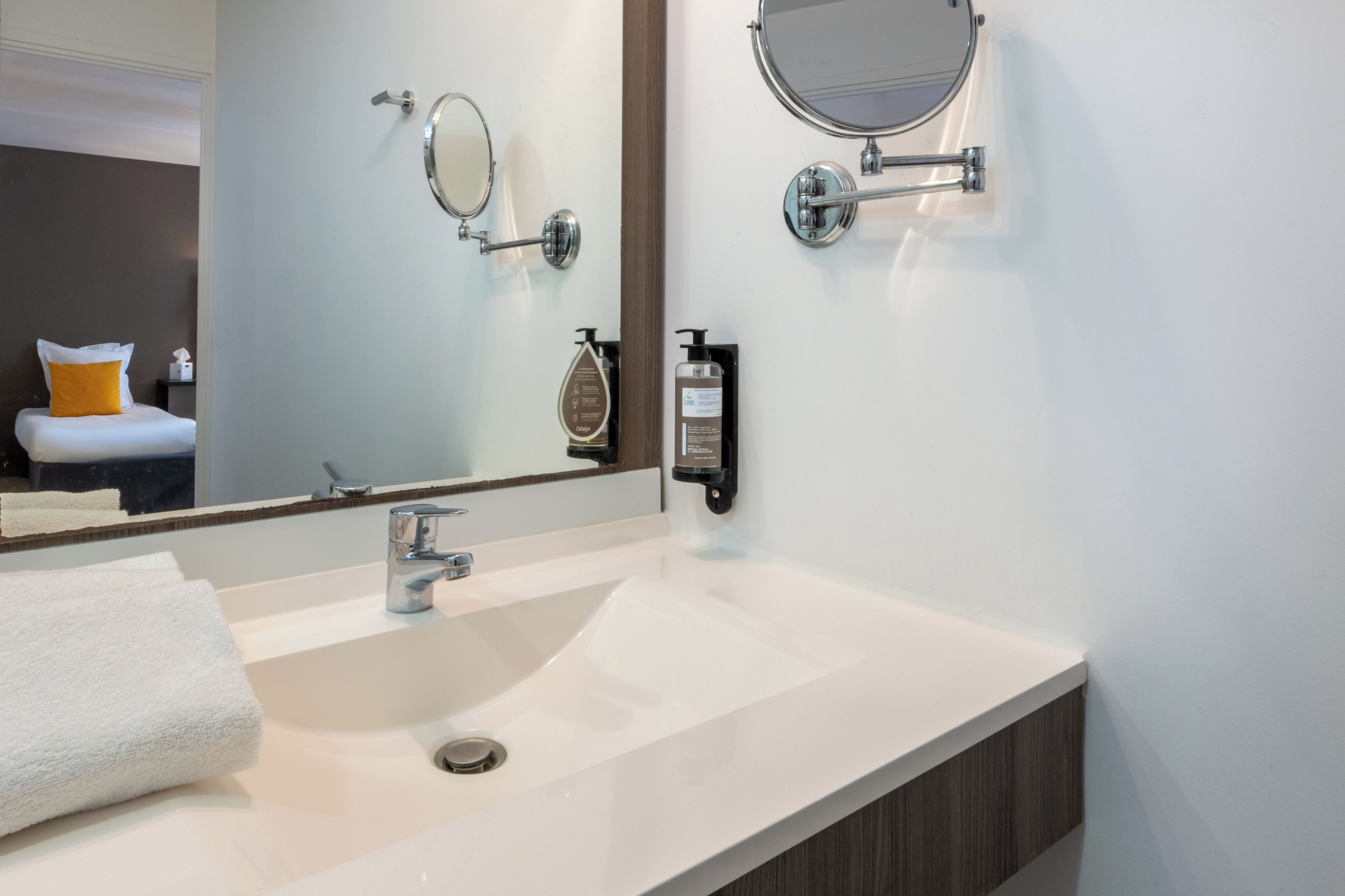 A modern bathroom with a large mirror, a sink, and toiletries.