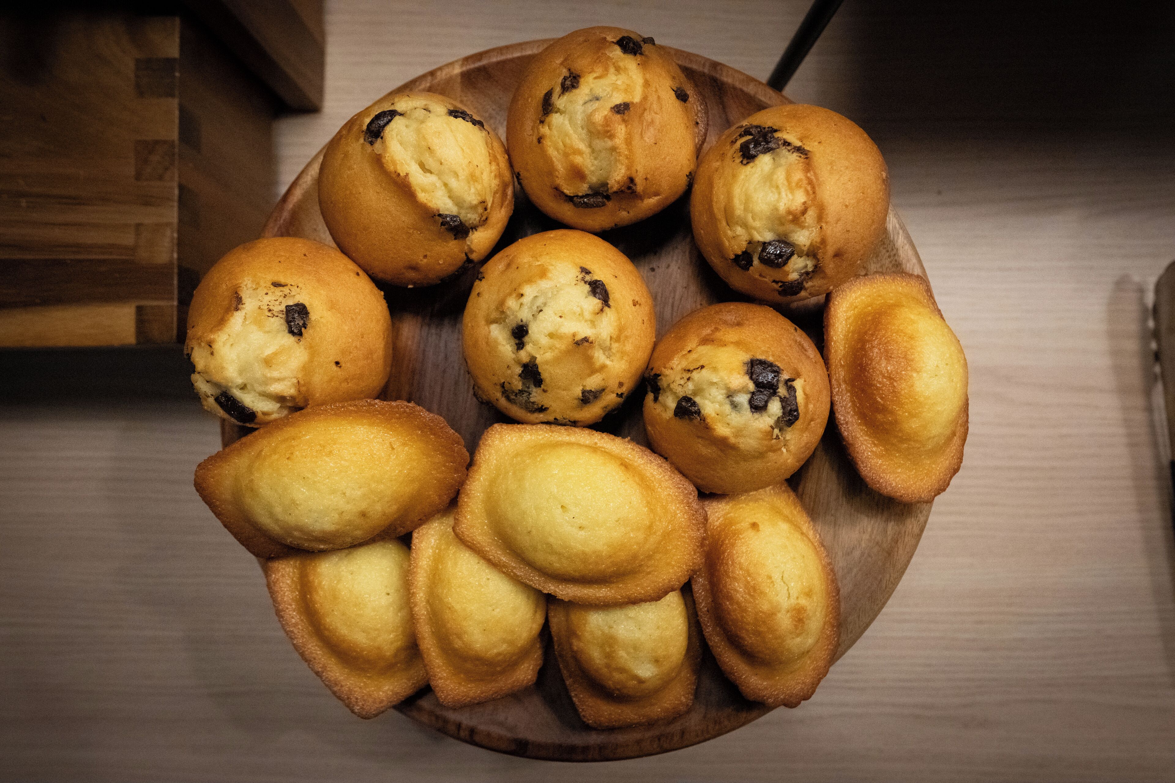 Un plateau en bois contenant divers types de pâtisseries, notamment des muffins et des biscuits.