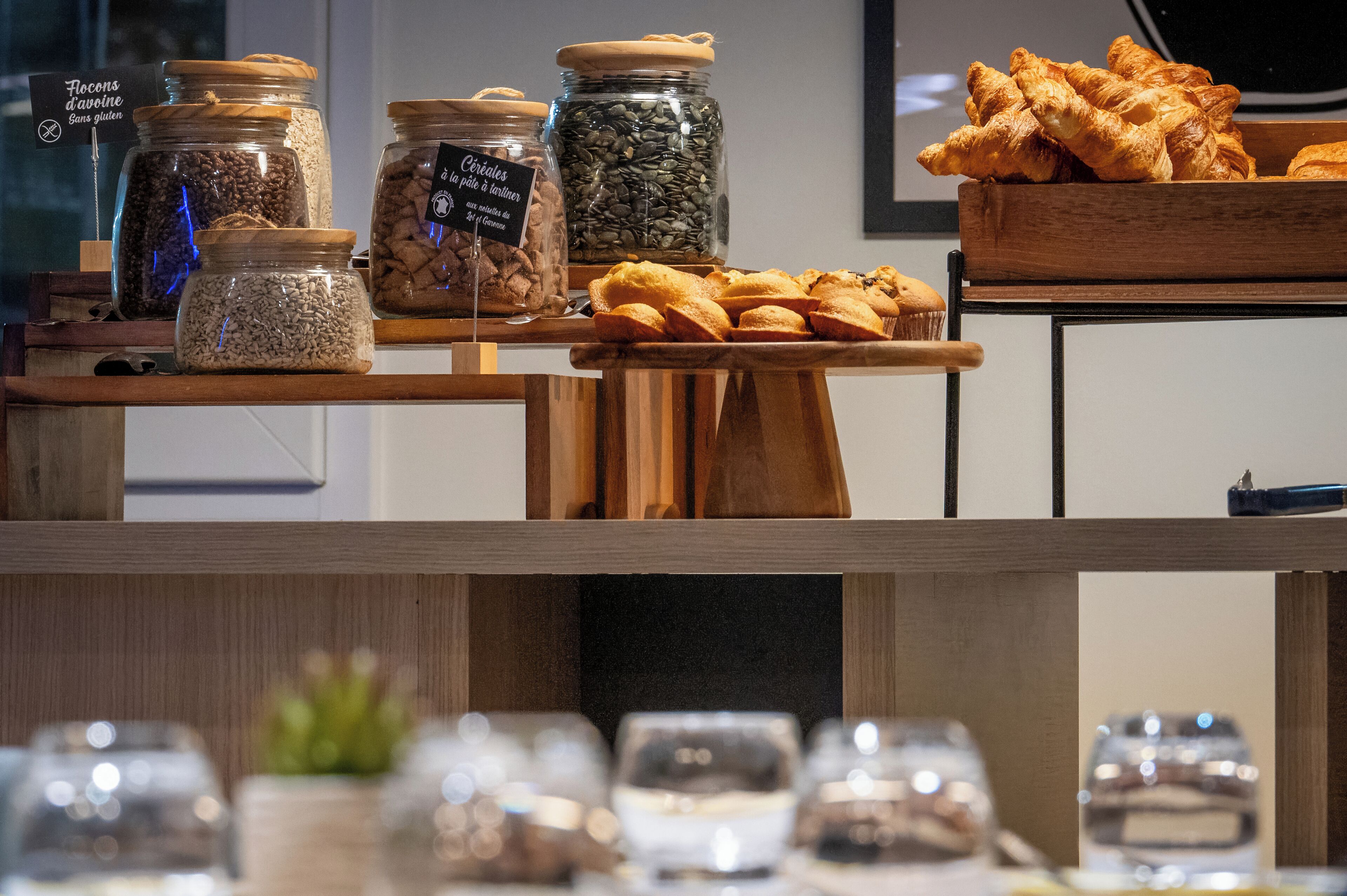 Une présentation de divers produits alimentaires, notamment des bocaux de graines et des pâtisseries, disposés sur des étagères en bois.