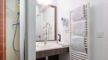 Une salle de bain moderne équipée d’une douche, d’un lavabo, d’un miroir et d’un porte-serviettes.