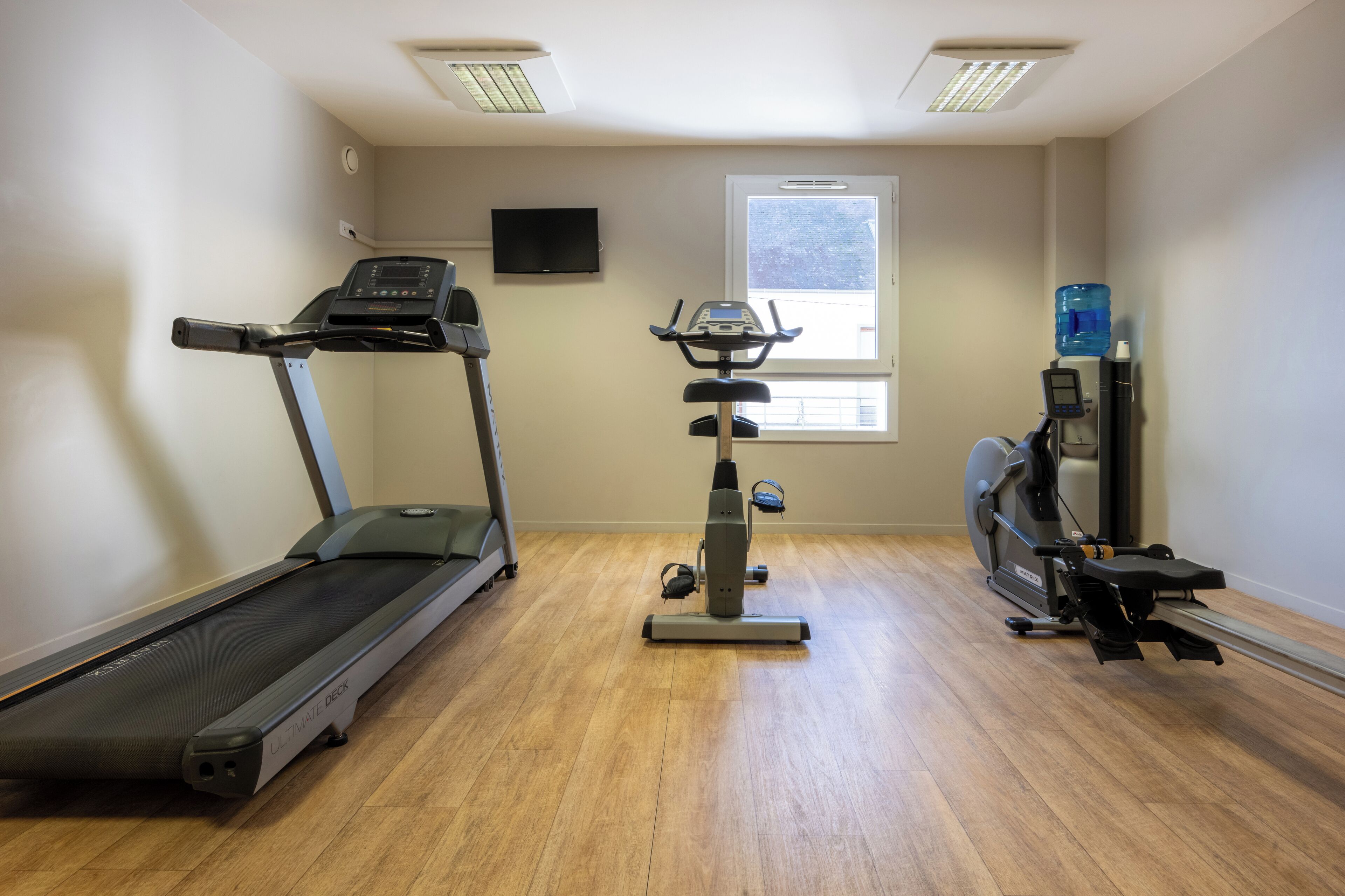 Un gimnasio con cinta de correr, elíptica y bicicleta estática.