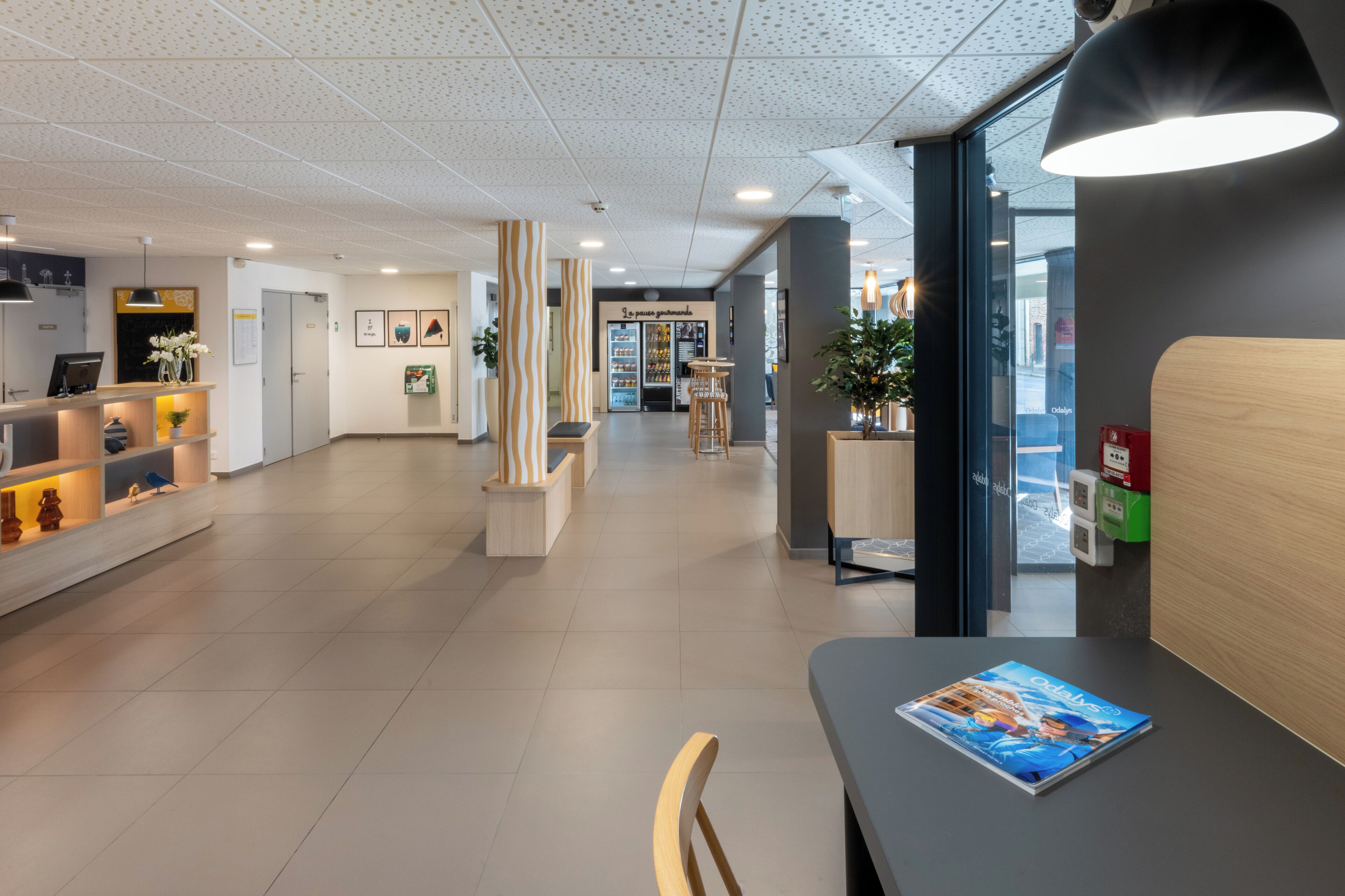 A modern reception area with a reception desk, seating, and a vending machine.