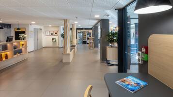A modern reception area with a reception desk, seating, and a vending machine.