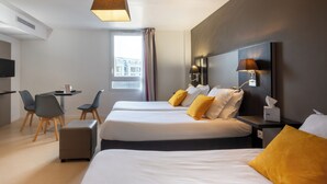 A hotel room with two beds, a desk, chairs, and a TV.