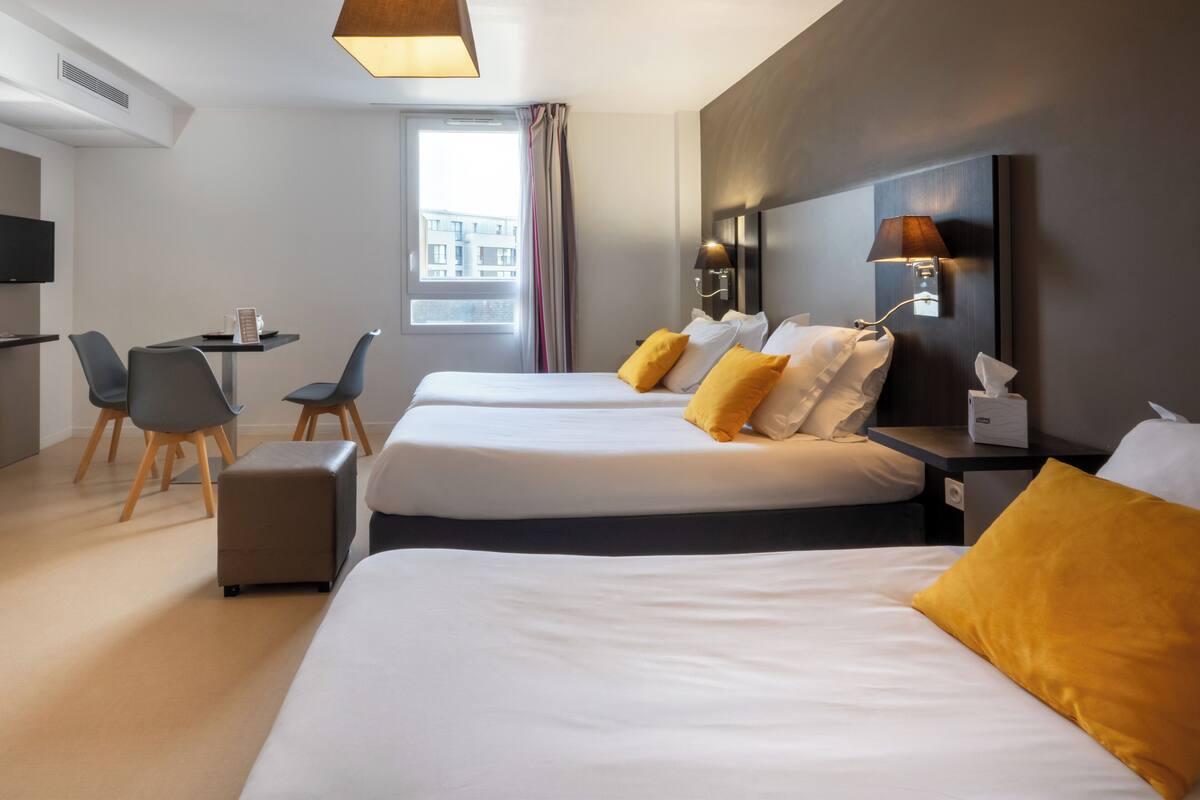 Une chambre d’hôtel avec deux lits, un bureau, des chaises et une télévision.
