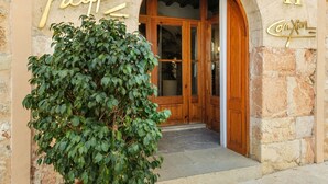 Un bâtiment en pierre avec une enseigne indiquant « Restaurant H » et une grande plante en pot devant l’entrée.