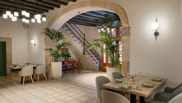 Un espace repas agrémenté d’une arche en pierre, d’un escalier et de plantes en pot.