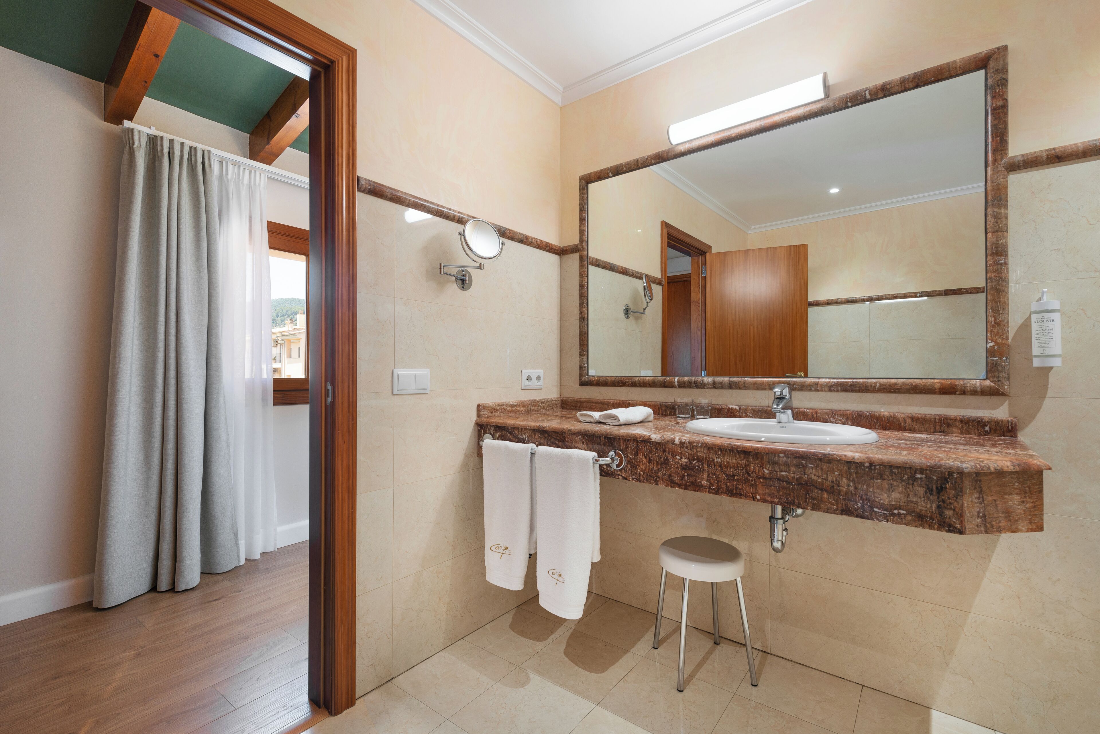 Une salle de bain avec un lavabo en marbre, un grand miroir et une porte à cadre en bois.