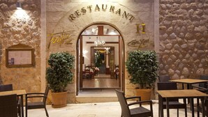 L’entrée d’un restaurant se caractérise par une façade en pierre, un arc et des plantes en pot.