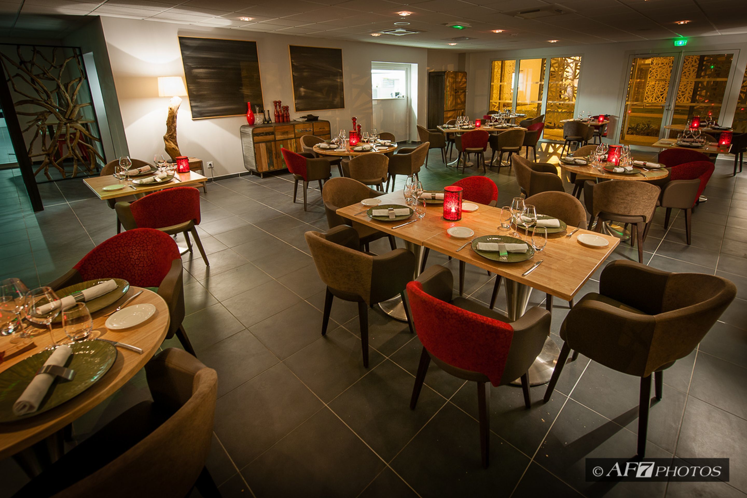 Un restaurante con varias mesas y sillas, dispuesto con mantelería y velas.