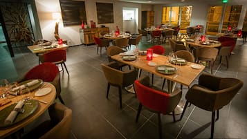 Un restaurante con varias mesas y sillas, dispuesto con mantelería y velas.