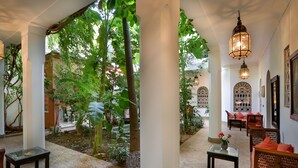 A spacious indoor garden with a brick floor, wooden furniture, and decorative lanterns. - Riad Dar El Assafir (Marrakech)