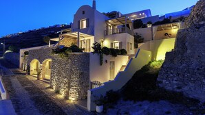 Una villa moderna con fachada de piedra, varios balcones y una escalera que conduce a los niveles superiores.