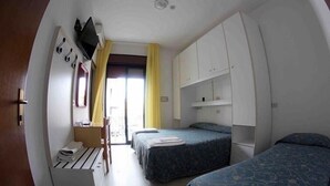 A compact hotel room with two beds, a desk, a chair, a TV, and a window with curtains. - Hotel Sorrento (Jesolo)