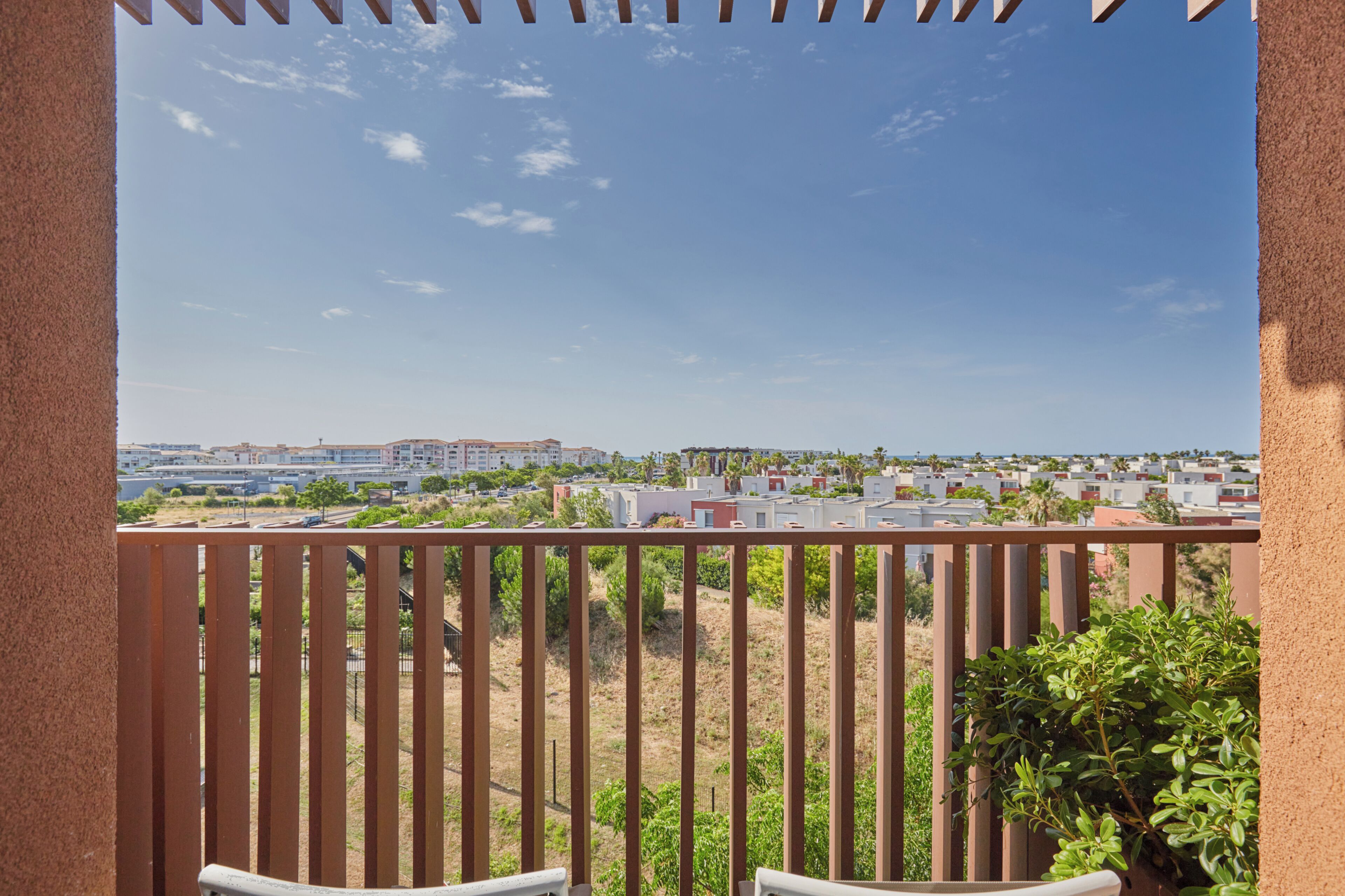 A balcony with a view of a residential area, including houses and a distant building.