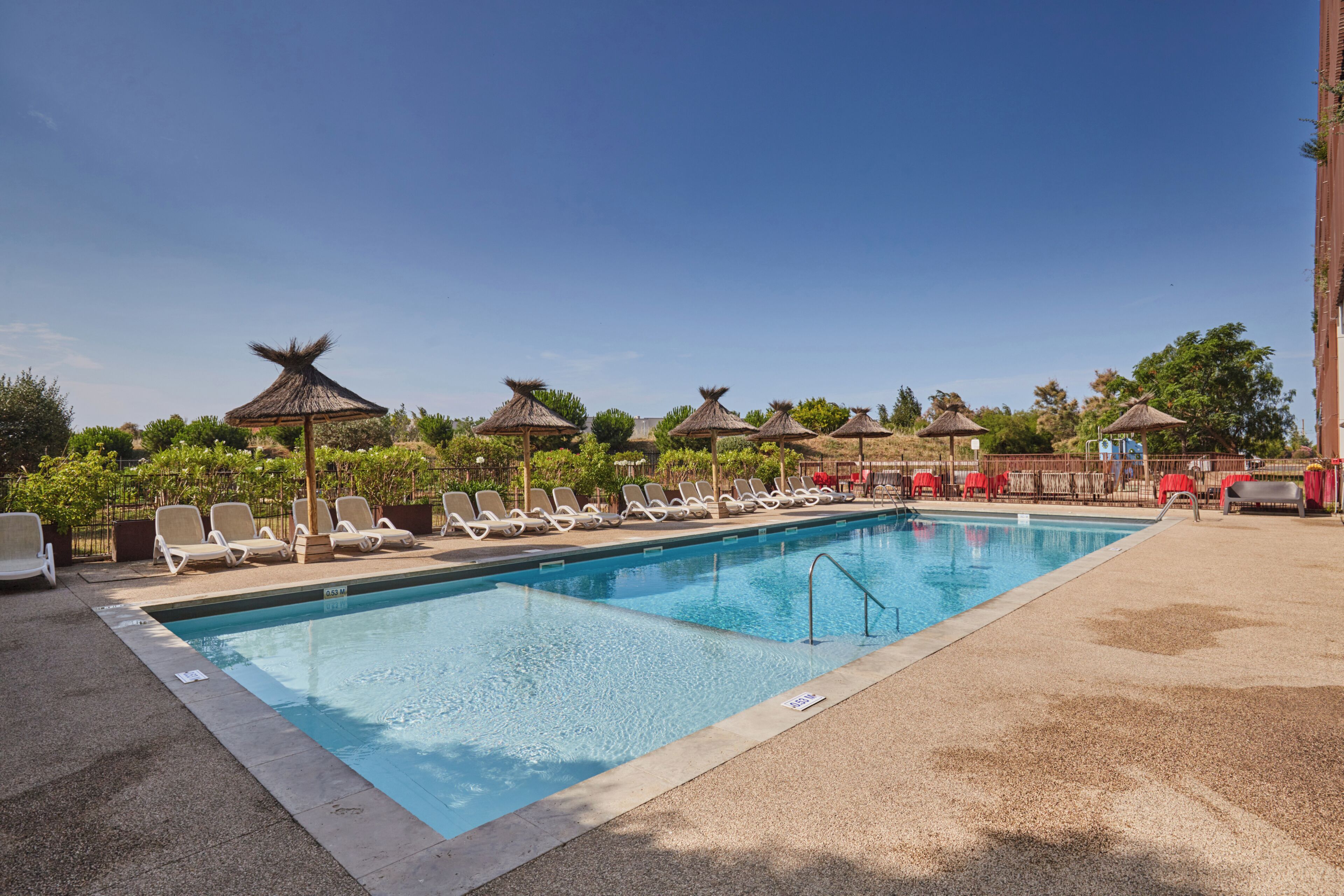 A swimming pool with lounge chairs and thatched umbrellas.