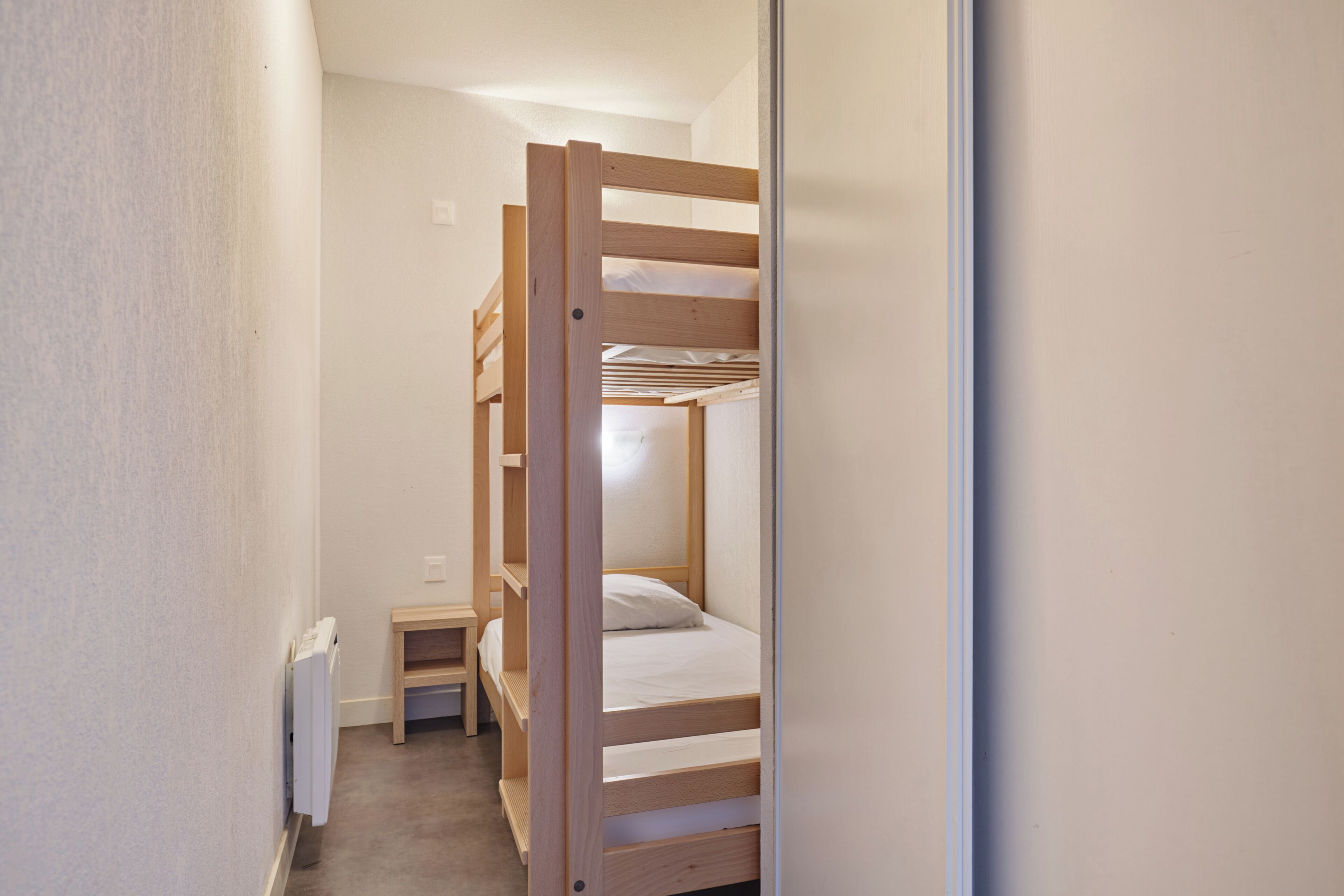 Habitación con literas, una mesita pequeña y un radiador.