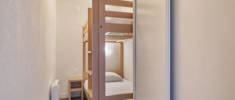 Habitación con literas, una mesita pequeña y un radiador.