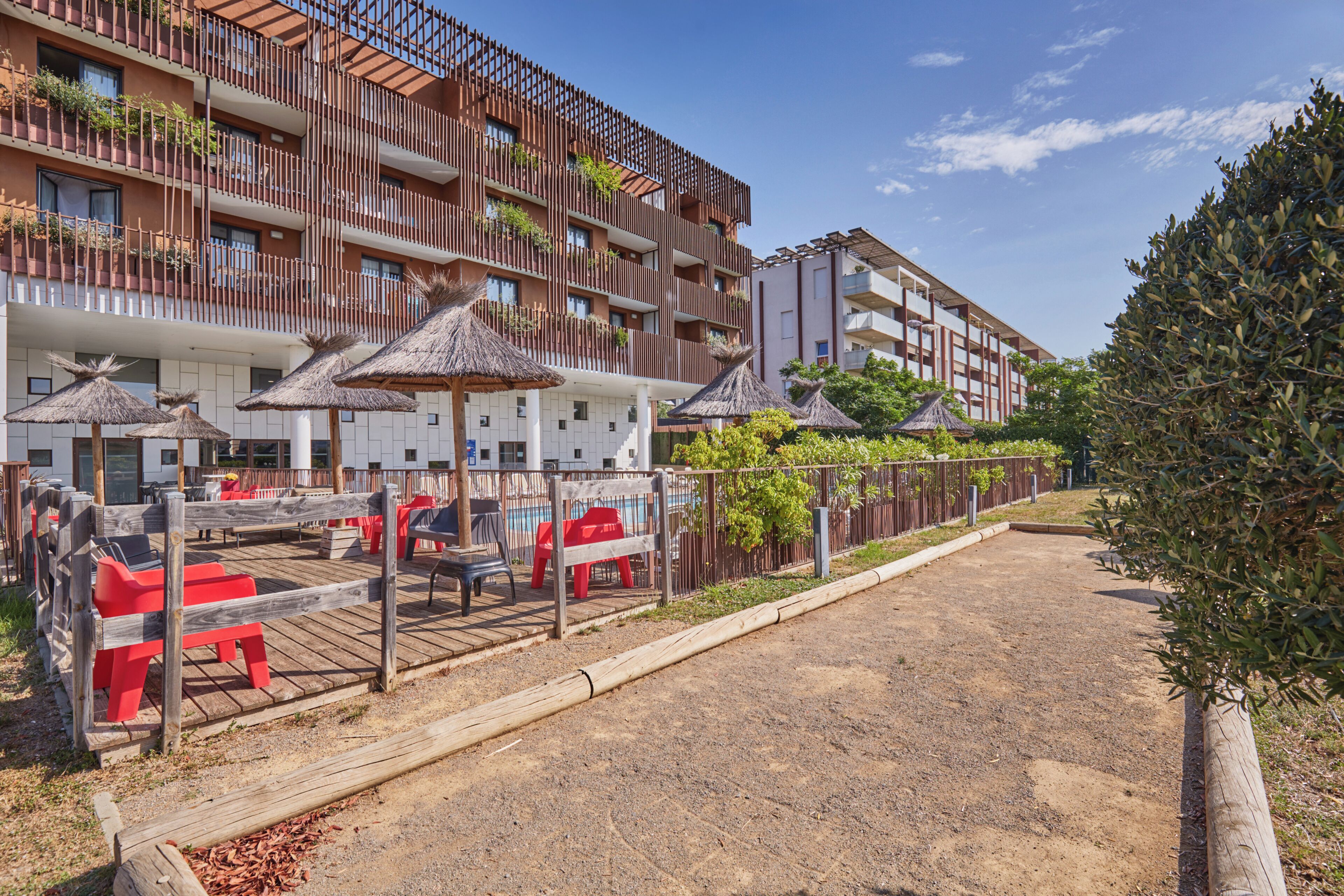 Hotel met terras, een onverhard pad en een hek.