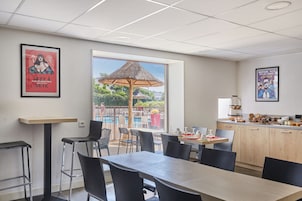 A modern dining area with a pool view, bar stools, and a kitchen area.